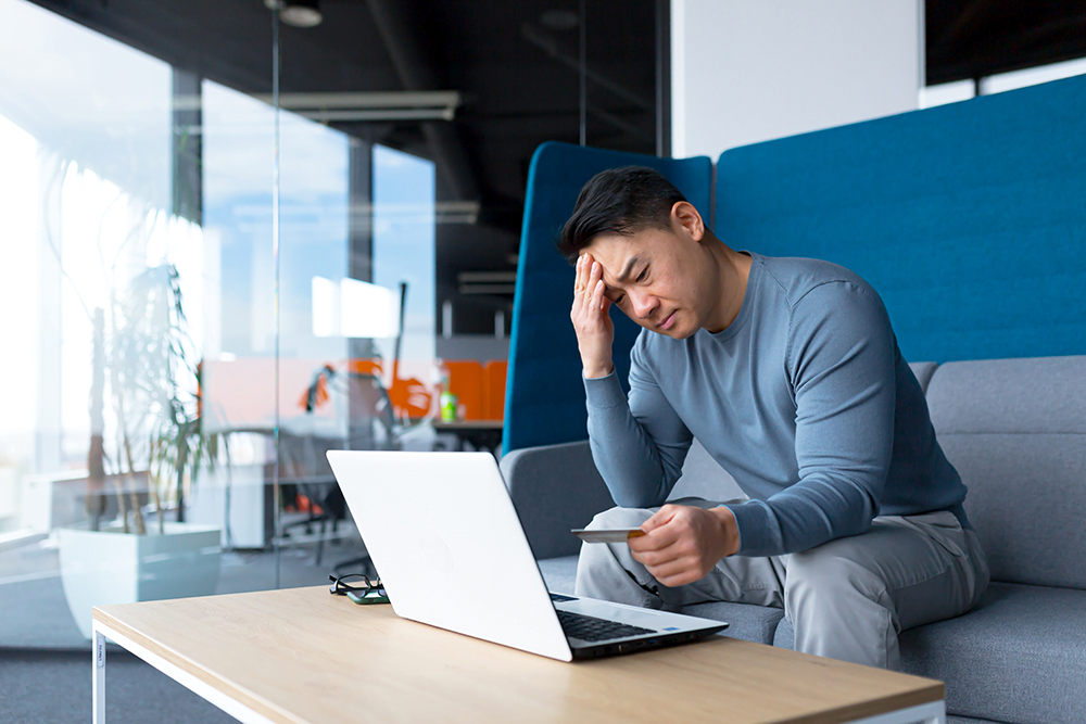 pixalink-annoyed-asian-man-trying-to-do-banking-with-laptop